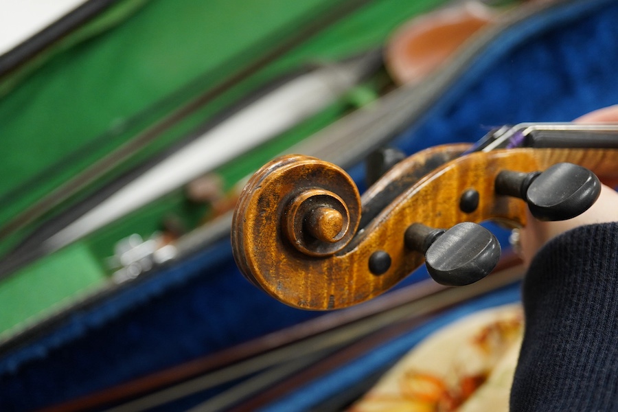 Four cased violins; an early 20th century violin, body 36cm, fitted with a microphone pick up taking a quarter inch jack plug, an early 20th century half size violin, body 32cm, and two student violins. Condition - poor